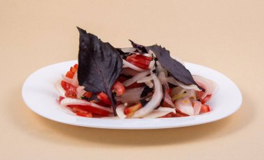 Beyaz plaka ince dilimler halinde kesilmiş domates ve soğan salatası ile