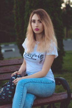 parkta bankların üzerinde bir sırt çantası ile kız