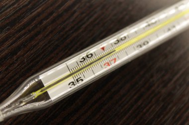 Yakın çekim yüksek sıcaklık santigrat derece Cheleo-çek vücutta için gösteren bir koyu ahşap arka plan, termometre.