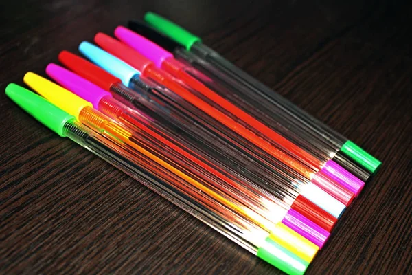 Multi Gekleurde Pennen Een Donkere Houten Achtergrond Gerangschikt Een Rij — Stockfoto