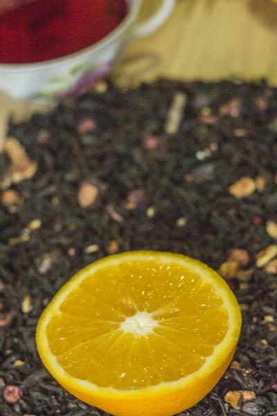 Naranja sobre un fondo de té de hierbas sueltas sobre un fondo de madera — Foto de Stock