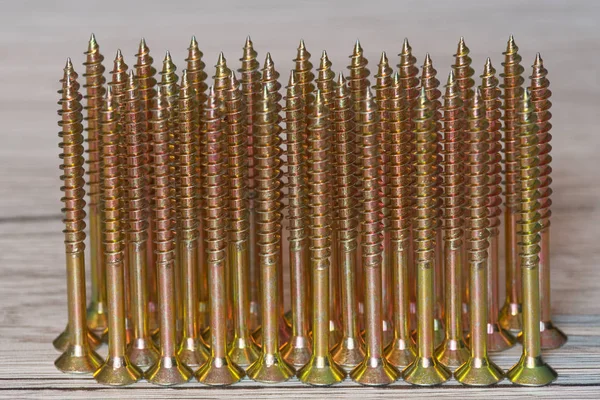 Sarı vidayı baş aşağı bir satır ahşap arka plan üzerinde duruyorsun