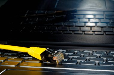 Klavyede yalan ve ekranda yansıyan sarı Ethernet kablosu