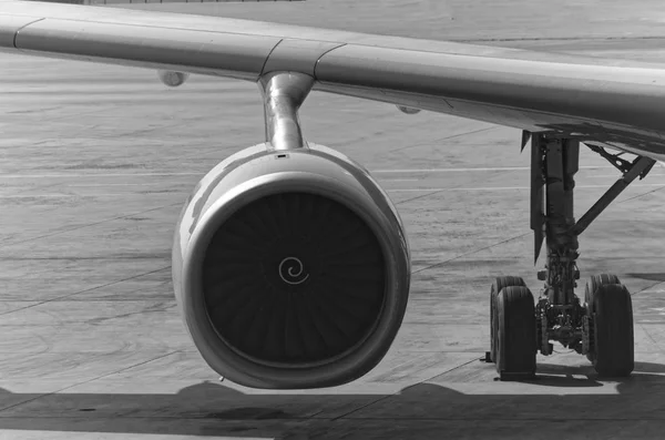 Black and white photo of an airplane engine and a gear with a part o a wing