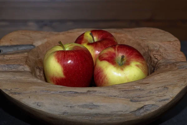 Close-up of Three apples in a wooden bowl