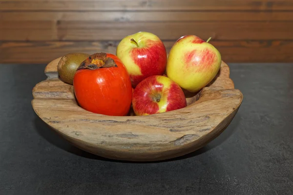 Szene von Früchten in einer hölzernen Schüssel auf einem dunklen Tisch — Stockfoto