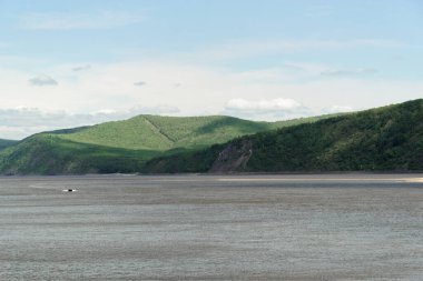 Scenic view of motorboat on Amur river and forested hills on the shore against blue sky, Komsomolsk-on-Amur, Russia clipart