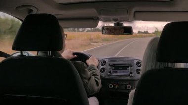 Bir yolcu manzaralı bir yolculukta eşlik ederken bir sürücü aracı kontrol eder. Gösterge paneli ve dikiz aynası bir yol yolculuğunun deneyimini gösteriyor..