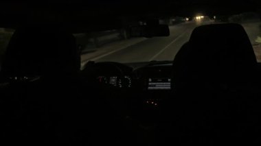 Aracın içinden görüldüğü gibi gece sürmek, gösterge paneli ışıkları ve çevre kentsel çevre, güvenlik ve gece ulaşımını ön plana çıkarmak. Bir seyahat hissi ve...