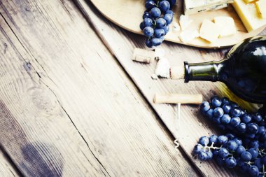 Bir şişe şarap, üzüm ve ahşap masa üzerinde peynirli mantarlar