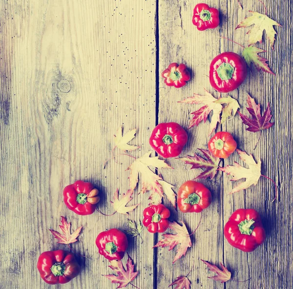 Jasně Červené Papriky Podzimní Listí Dřevěné Pozadí — Stock fotografie