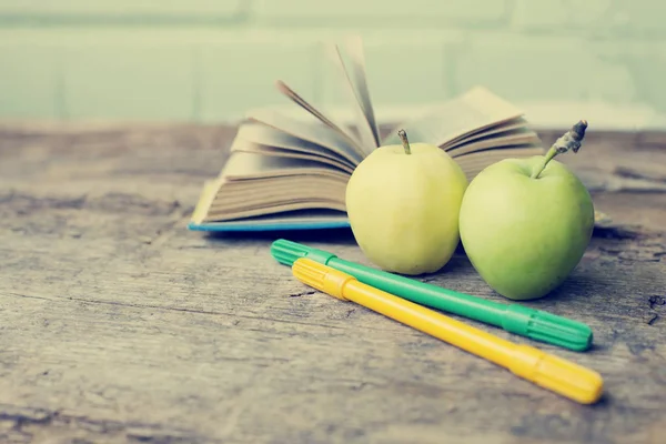 closeup view of apples with book and pencils over wooden table