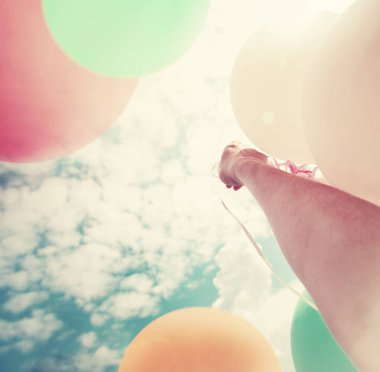 Gökyüzü arka plan üzerinde renkli büyük balonlar tutan el