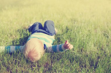 Mutlu yürümeye başlayan çocuk yaz çayır üzerinde rahatlatıcı güneşli parkta çim