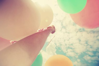 Gökyüzü arka plan üzerinde renkli büyük balonlar tutan el