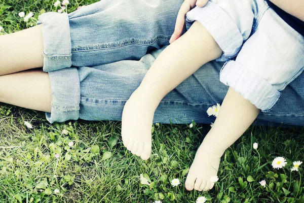 Beyaz çiçekli yeşil çimenlerin üzerinde yalınayak insanlar