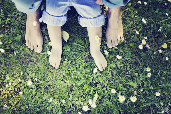 Barefooted people on green grass with white flowers