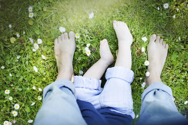 Barefooted people on green grass with white flowers