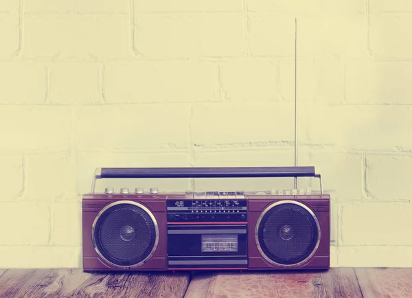 Retro radio player with buttons and antenna on white wall background