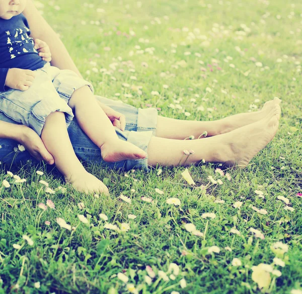 日当たりの良い公園で母親と一緒に緑の芝生でくつろいで幸せな幼児の少年 — ストック写真
