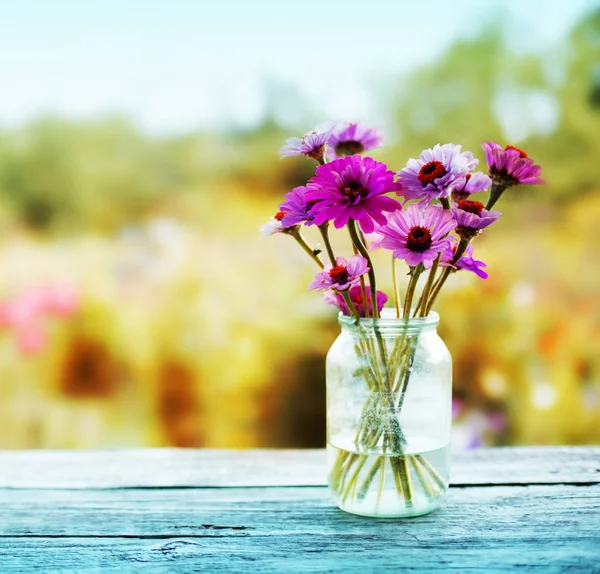 屋外の素朴なテーブルの上の瓶に新鮮な菊 — ストック写真