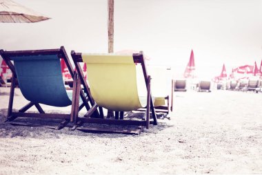 Plaj arka plan ile çok renkli şezlonglar ve şemsiyeler deniz kenarında