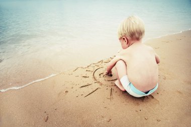 Kum üzerinde çizilmiş Paz Üye ile oynarken erkek bebek 