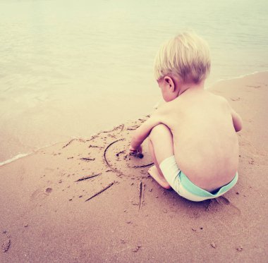 Kum üzerinde çizilmiş Paz Üye ile oynarken erkek bebek 