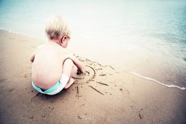Kum üzerinde çizilmiş Paz Üye ile oynarken erkek bebek 