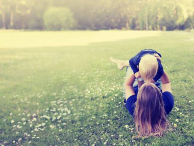 Güneşli park annesi ile yeşil çimenlerin üzerinde oynarken mutlu yürümeye başlayan çocuk