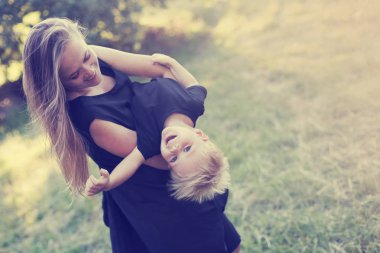 Güneşli parkta yürümeye başlayan çocuk evlat oynamaktan mutlu anne