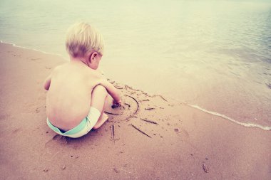 Kum üzerinde çizilmiş Paz Üye ile oynarken erkek bebek 