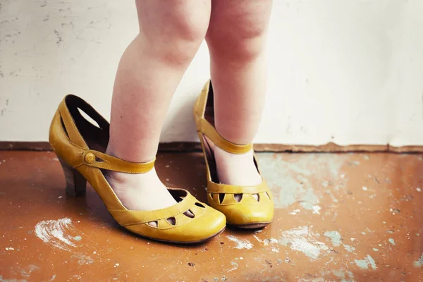 cropped image of little child wearing mothers shoes