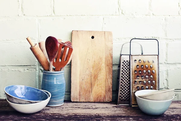Different kitchenware on wooden table on white wall background