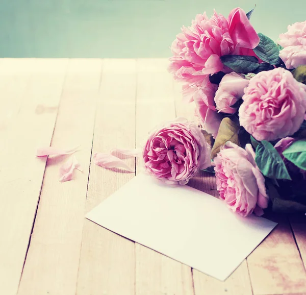 白紙の封筒と木製のテーブルにピンクの牡丹のバラ — ストック写真