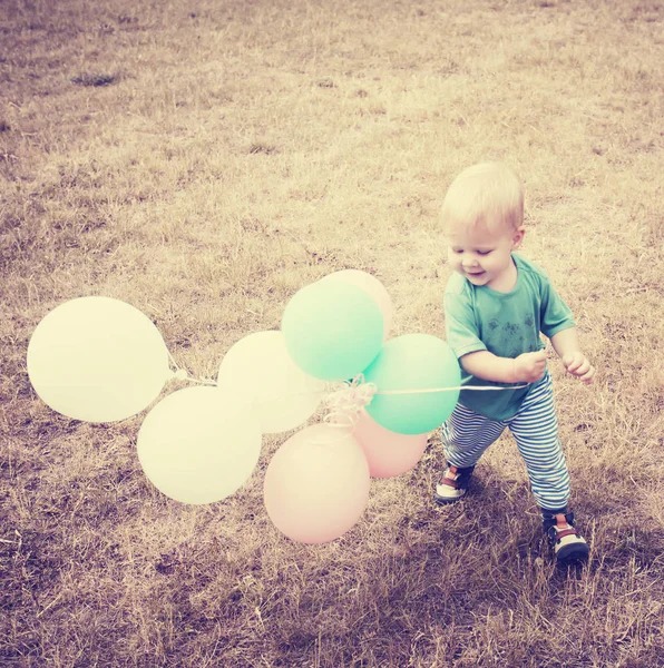 在夏日草地上玩五颜六色的气球的小男孩 — 图库照片