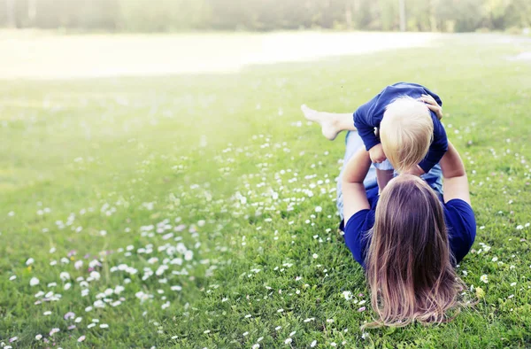 日当たりの良い公園で母親と一緒に緑の芝生で遊ぶ幸せな幼児少年 — ストック写真