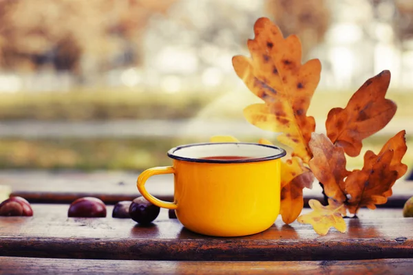 closeup view of mug with hot beverage against blurred trees in background