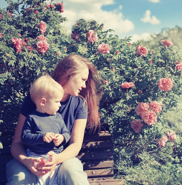 Happy Boy Sitting Bench Mother Blossoming Bushes Sunny Park — Stock Photo, Image