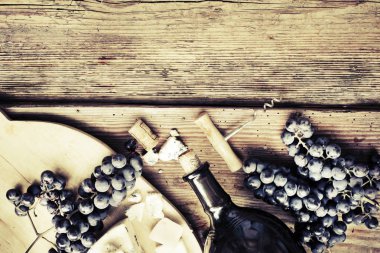 Şişe beyaz şarap, peynir, üzüm ve ahşap masa tarihinde mantarlar