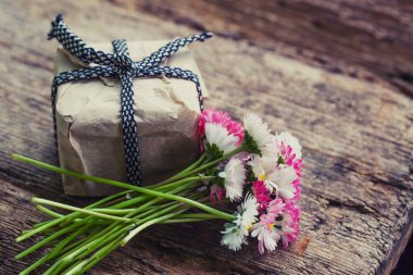 papatya ve hediye kutusu ahşap masa üstünde kurdele ile parlak buket