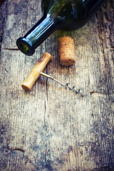 Wine bottle, cork and corkscrew on wooden background