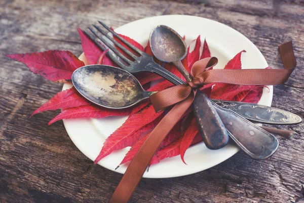 秋の紅葉と木製のテーブルの上の食器プレートのクローズ アップ ビュー — ストック写真