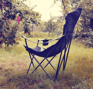 Katlanır sandalye ayakta ağaçlar arasında yeşil çimenlerin üzerinde