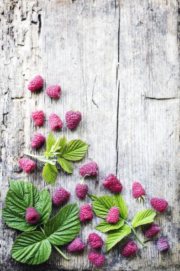 taze kırmızı ahududu ahşap arka plan üzerinde dağınık yaprakları ile