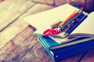 Renkli kalemler ve ahşap masa üzerinde kırmızı makas ders kitabı 