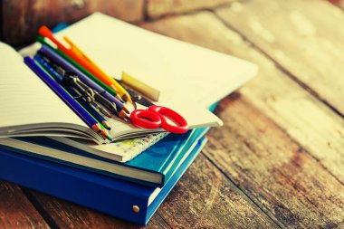 Renkli kalemler ve ahşap masa üzerinde kırmızı makas ders kitabı 