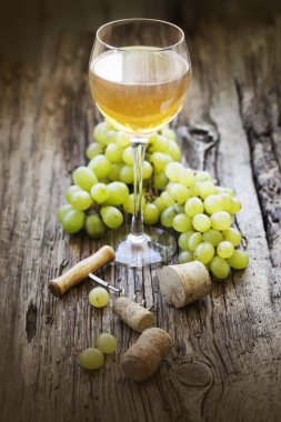 Şişe beyaz şarap gözlük, üzüm ve ahşap masa tarihinde mantarlar