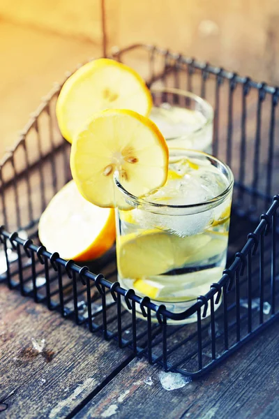 two glasses with lemonade in black iron basket on wooden table