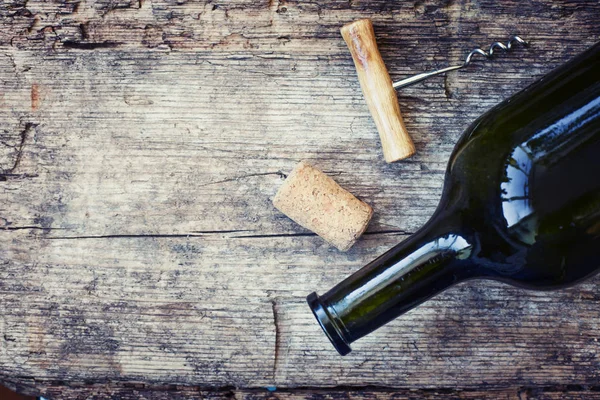 Wine bottle, cork and corkscrew on wooden background